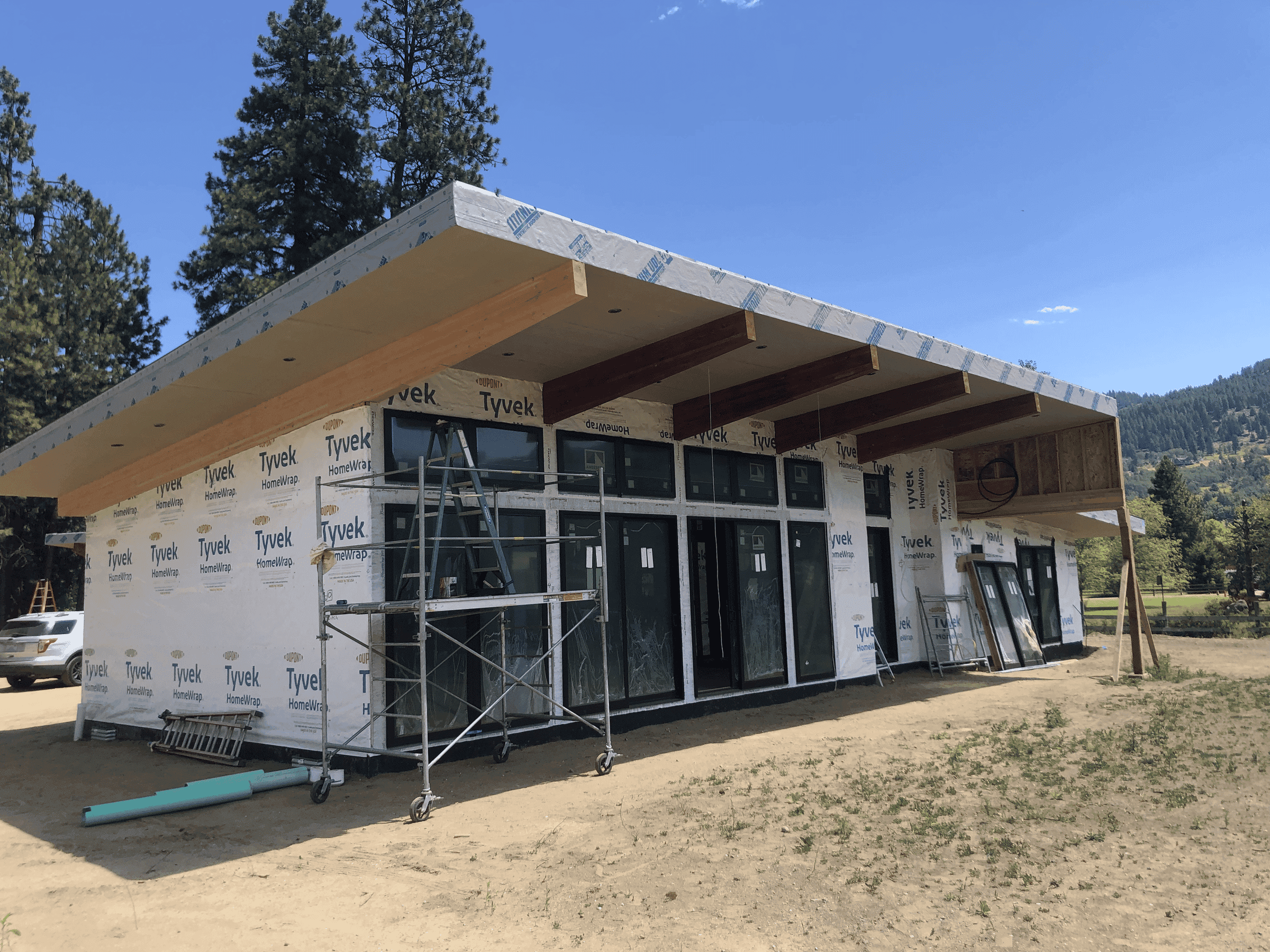 Exterior of home with large windows and wooden accents prior to siding and exterior finishes